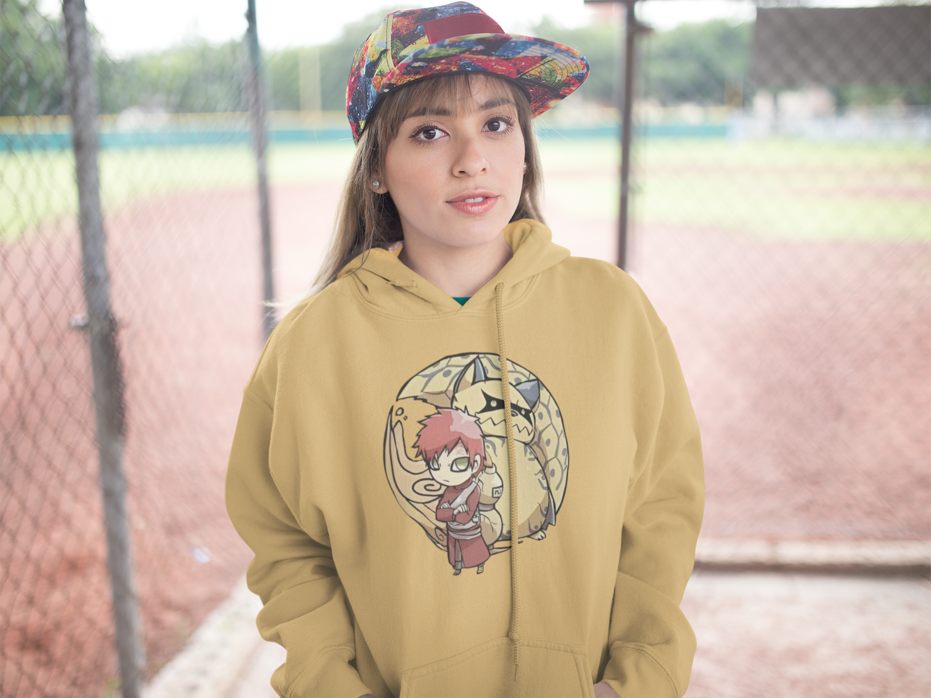 Person wearing a mustard yellow hoodie with a graphic design, standing outdoors.